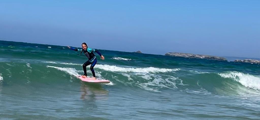 Benthe staat op haar surfboard in de golven